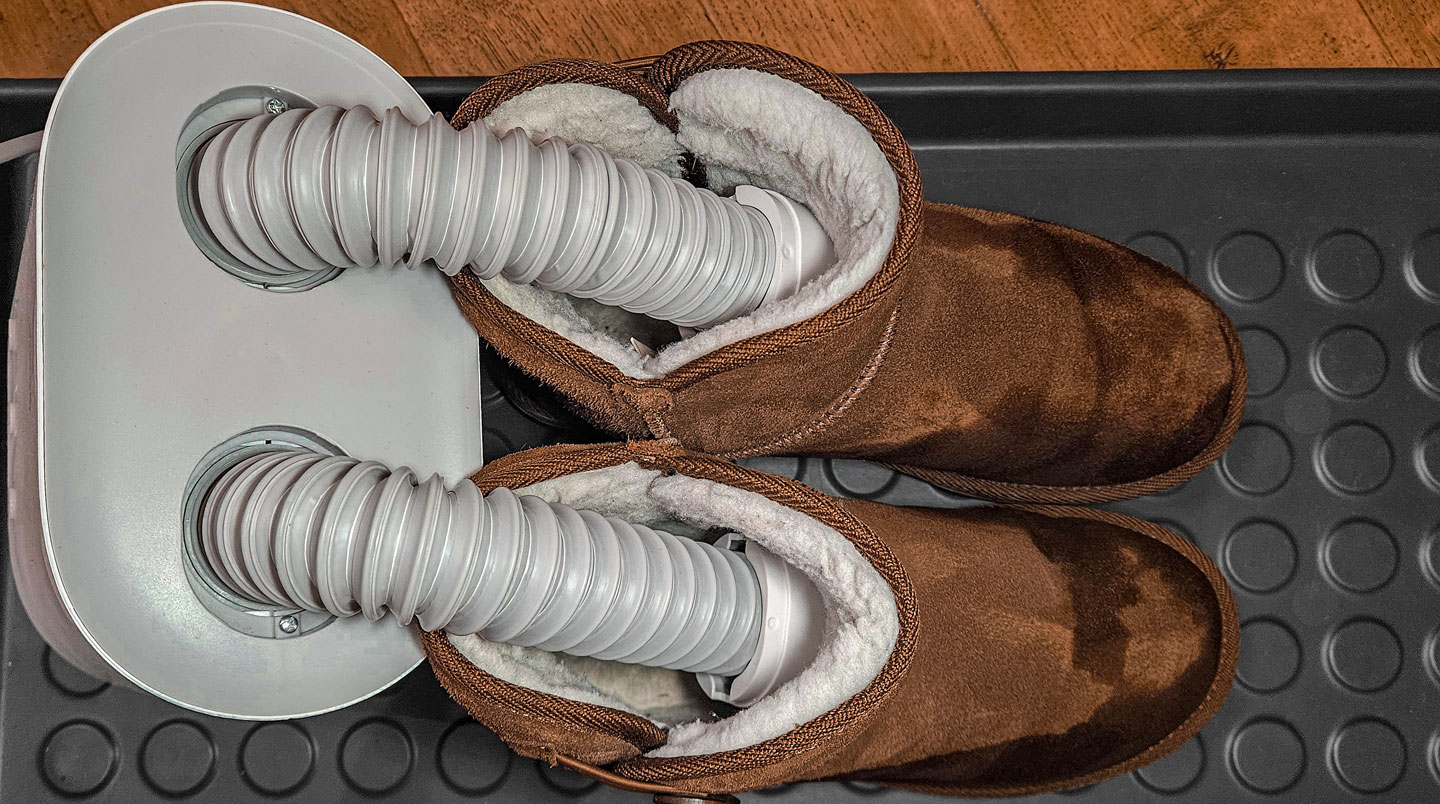 Gros plan sur un sèche-chaussures électrique moderne en fonctionnement avec des chaussures de ski posées dessus et une légère vapeur visible